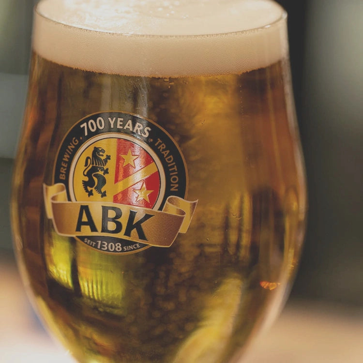 ABK pilsner in a munique glass. The ABK logo features prominently 